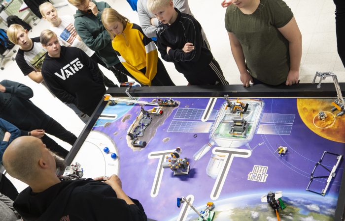 There are kids around a LEGO robot game table.