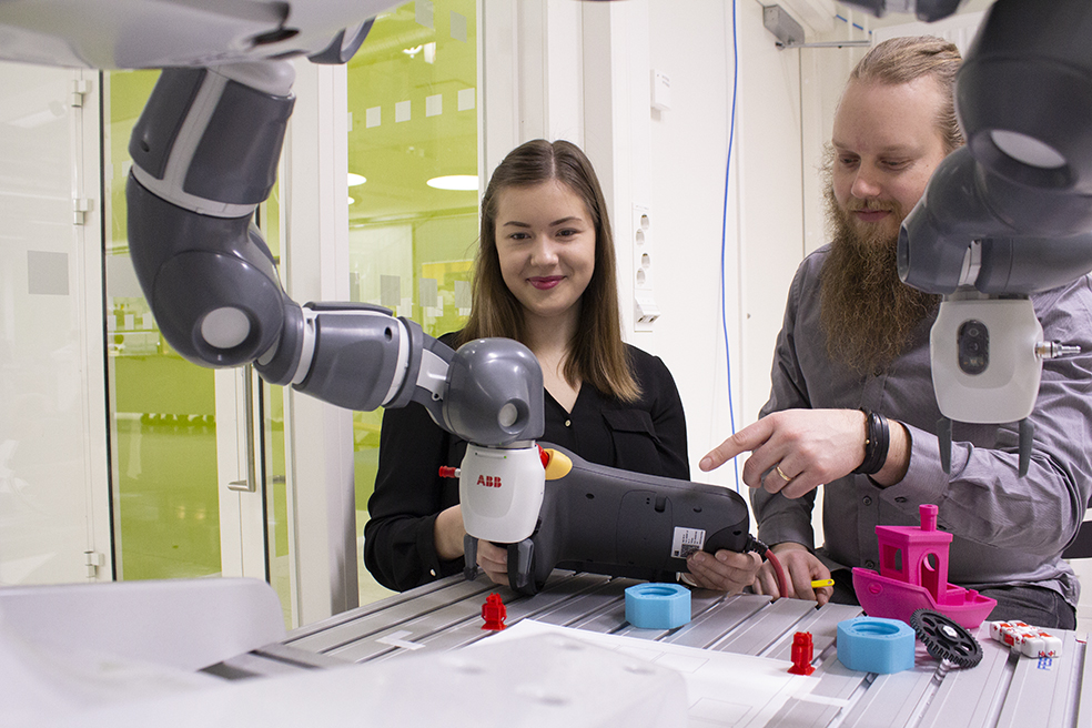 Robotiikka Akatemian opiskelijat Sanni ja Jani käyttävät ABB-robottia.