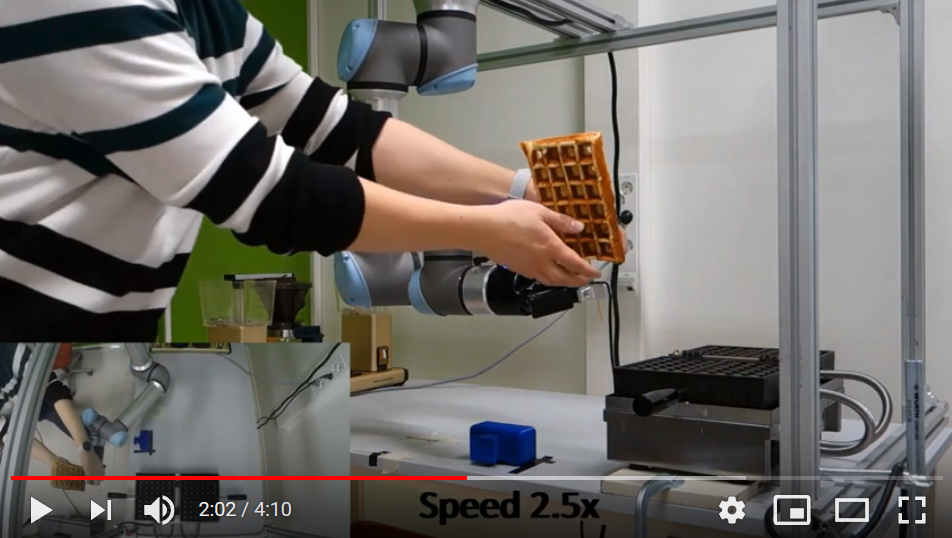 Kuvassa kuvakaappaus opiskelijoiden tekemästä demovideosta, jossa robotti avustaa kahvilatyössä.