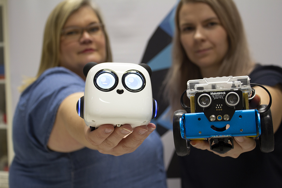 Pikkukuva Mirka Leino ja Janika Tommiska pitävät käsissään lapsille tarkoitettuja ohjelmoitavia robotteja.