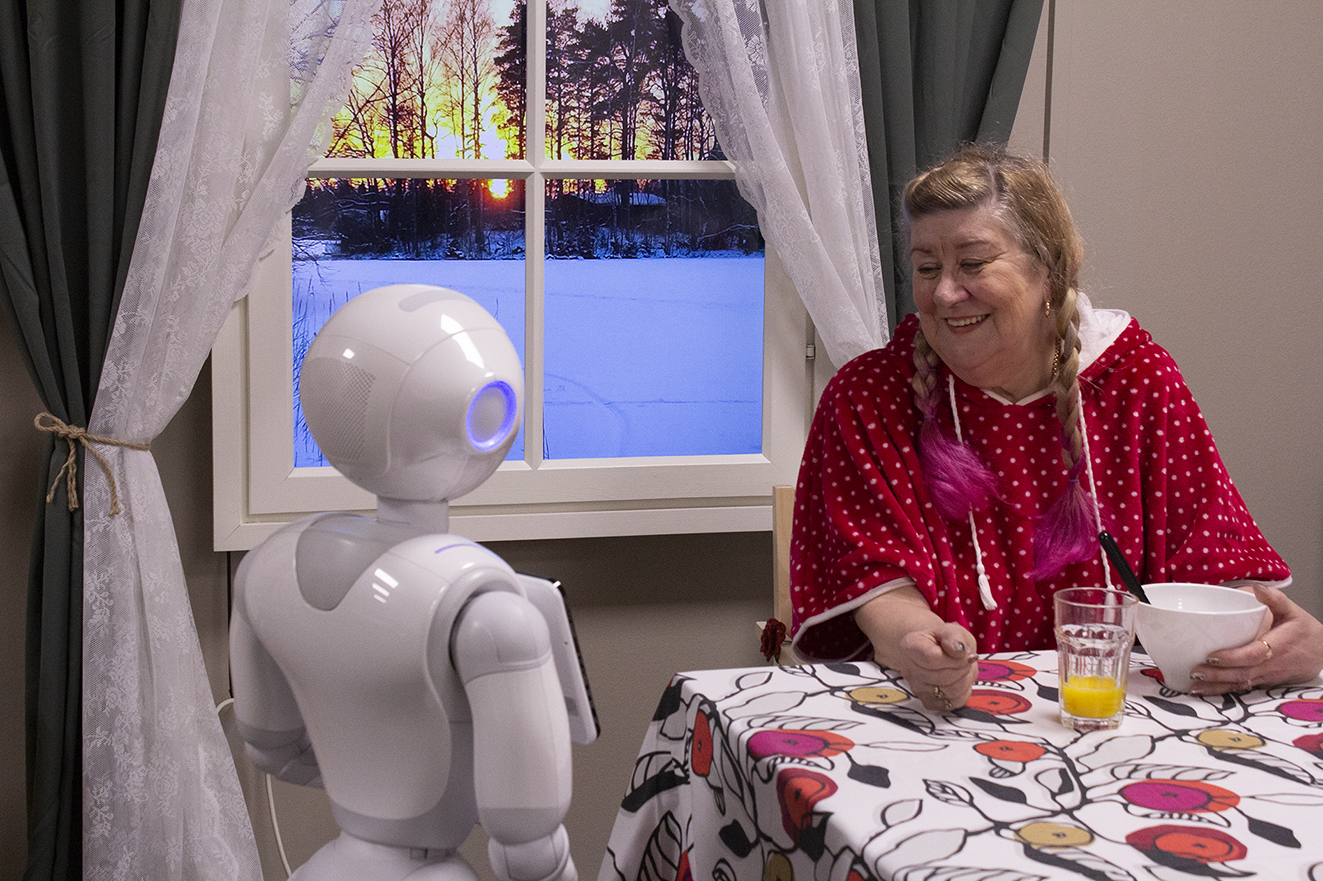 Kolmas Pienempi Ikäihminen seurustelee humanoidirobotin kanssa.