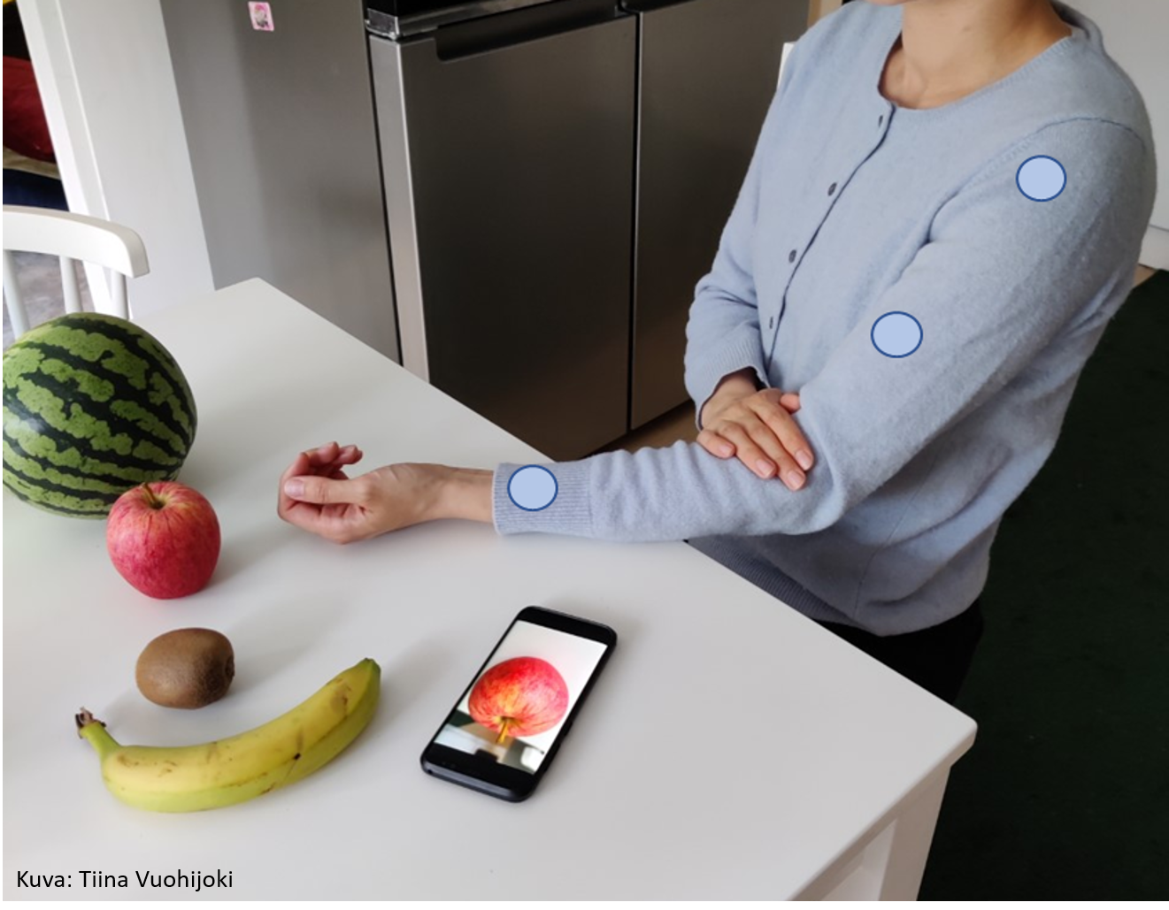 Älyvaateteknologian avulla ihminen valitsee pöydällä olevan hedelmän koskettamalla paitaansa.