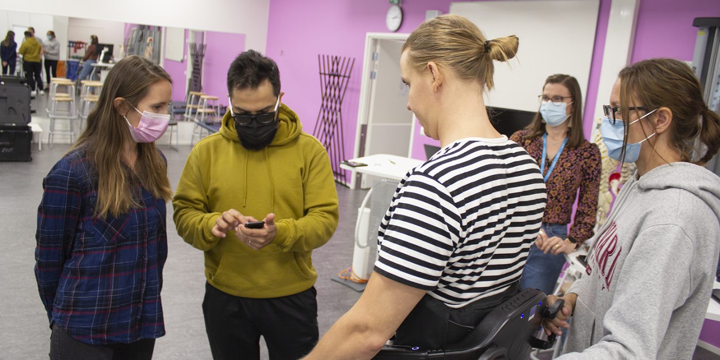 A man wearing exoskeleton, surrounded by people.