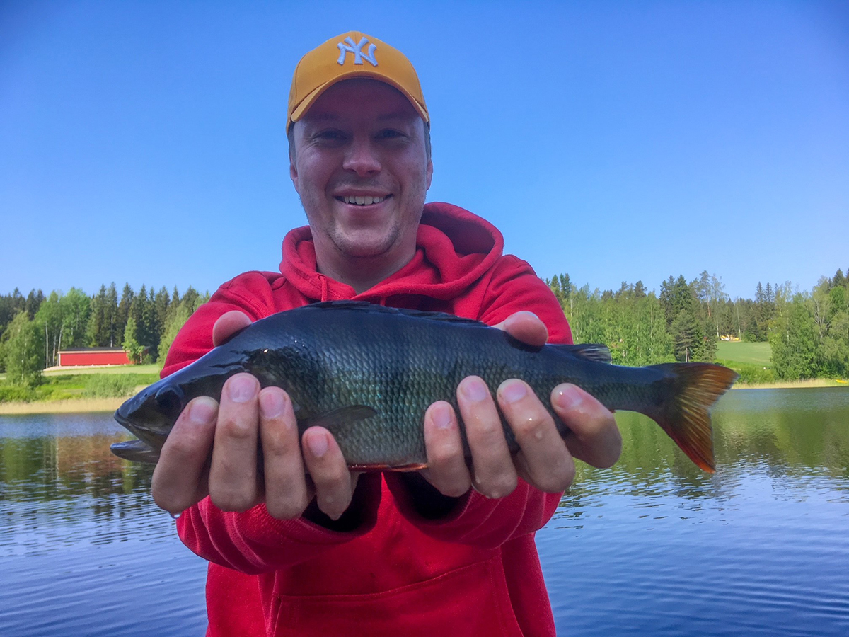 Lähikuvassa Peter Virtanen, joka pitää kalaa käsissään.