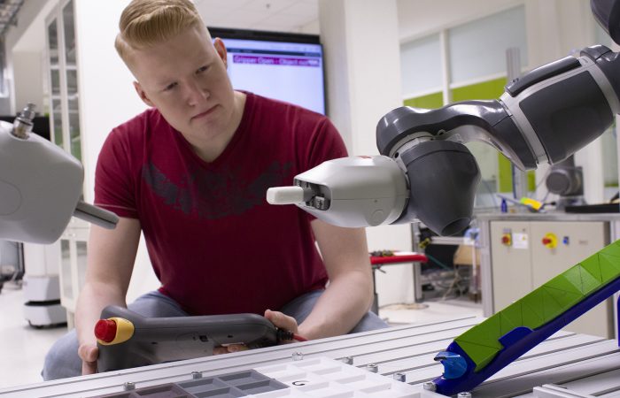 Close-up of the Yumi robot, with a student in the background.