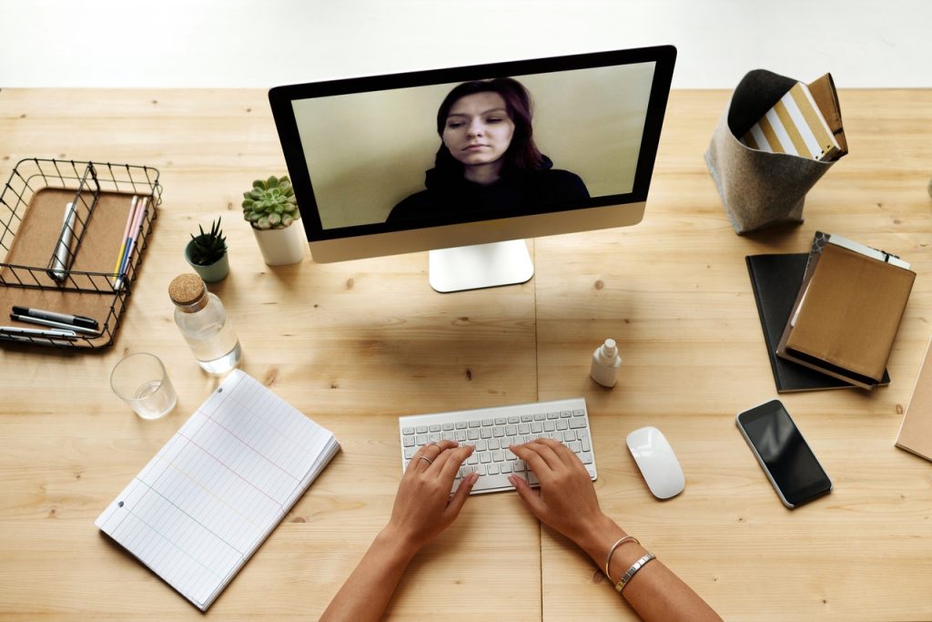 A woman is doing remote work. There's a screen, keyboard etc on the table. 