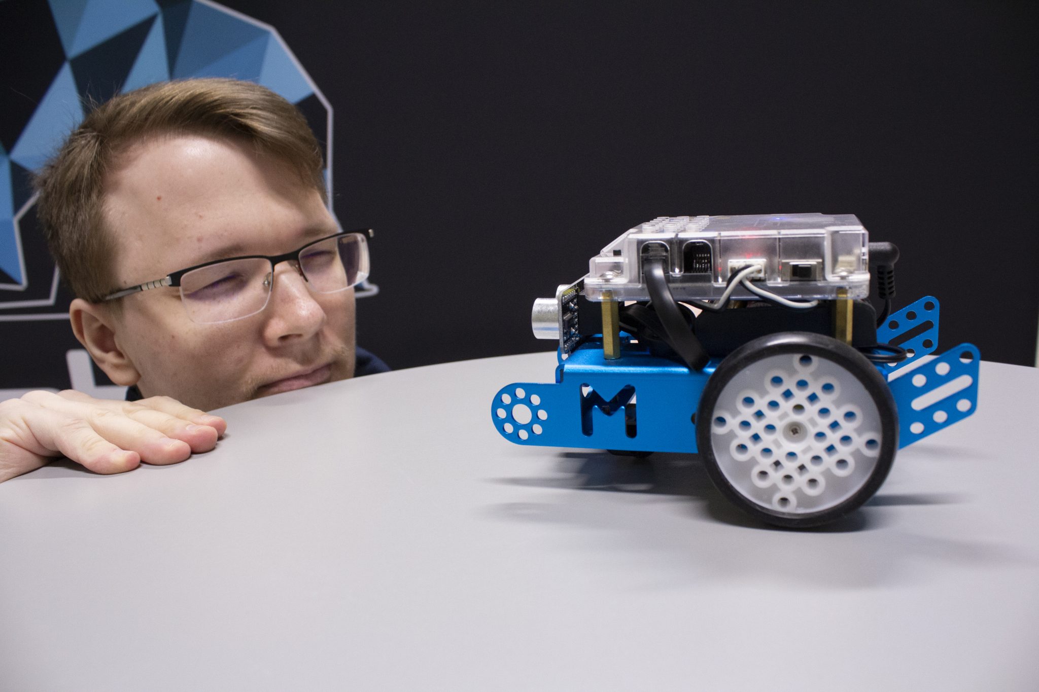 Closeup of student and a small robot. 