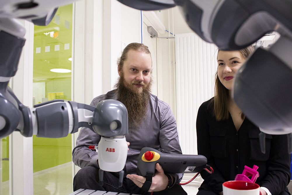 A woman and a man using a robot.