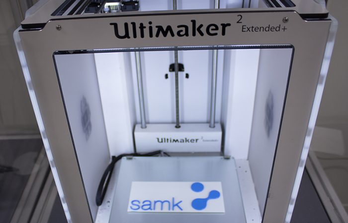 Close-up of a 3D-printer with SAMK's logo inside.