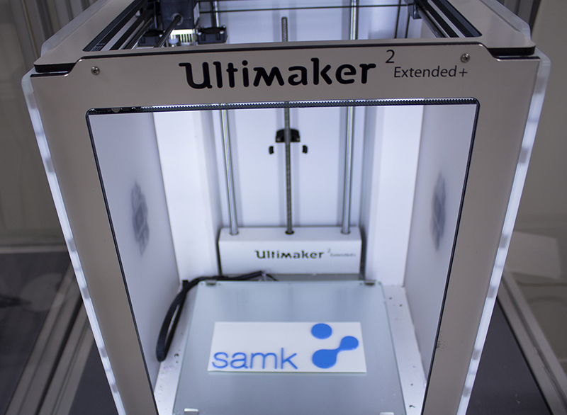 Close-up of a 3D-printer with SAMK's logo inside.