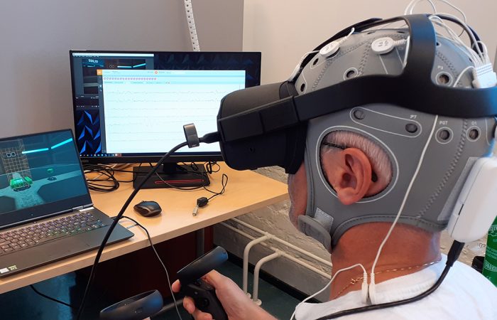 Miehellä päässä EEG-pipo ja VR-lasit.