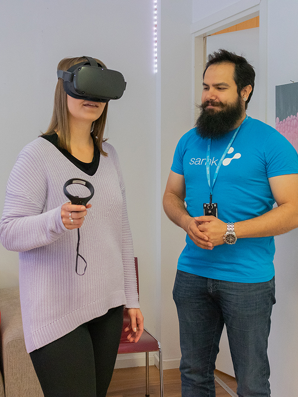 Naisella on päässään VR-lasit, ohjaaja seuraa vieressä.