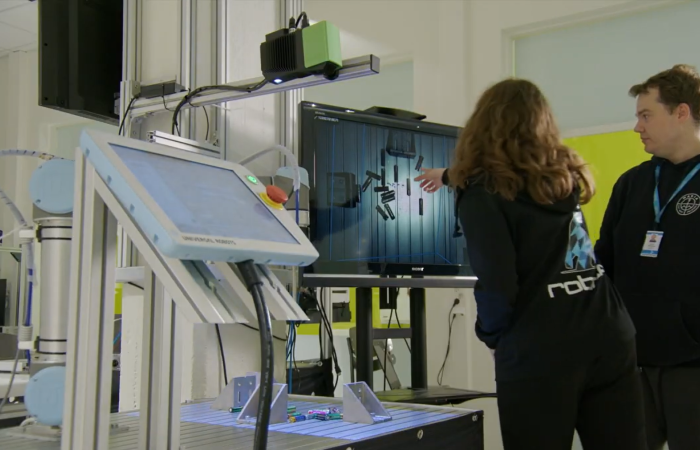 Kuvassa ruskeahiuksinen Johanna osoittaa paristoja näytöllä ja Juuso seuraa Johannan osoitusta.