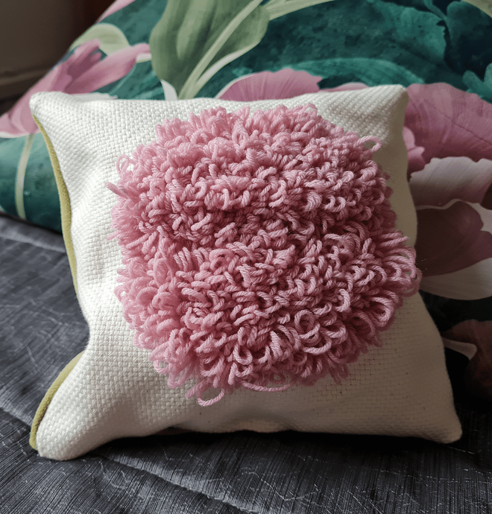 The picture shows a pale cushion with a pink section in the middle.