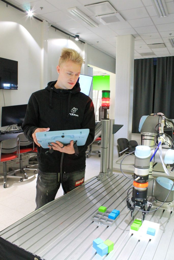 A male student controls a robot with a controller.