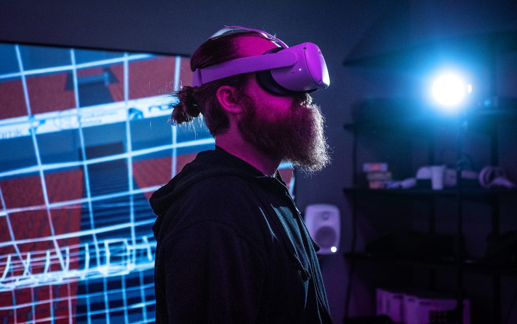 The photo shows a male person with VR glasses on his head and an image visible through the glasses on the back.