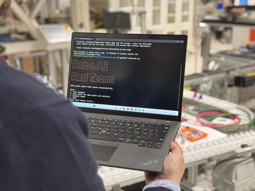 A man is holding a laptop in his hands. The screen reads RoboAI Red Team.