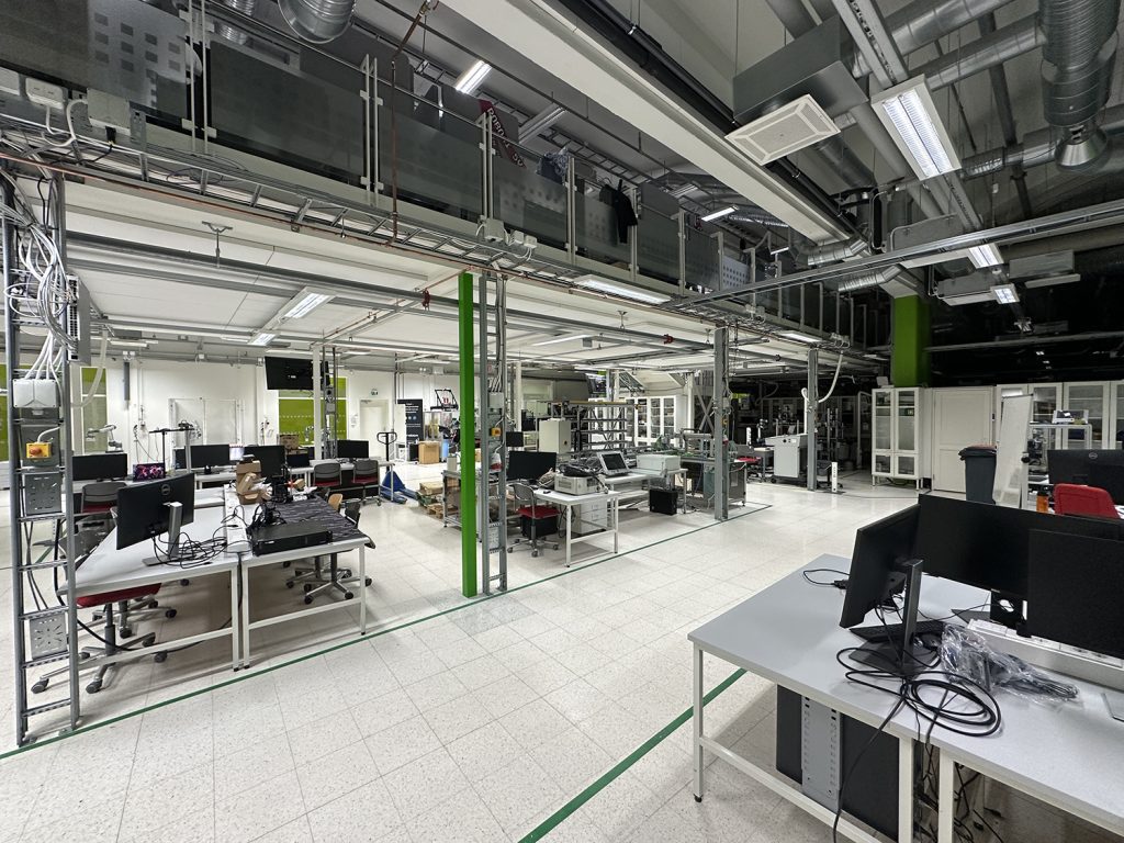 Yleiskuvaa laboratoriosta: työpöytiä ja tietokoneita.