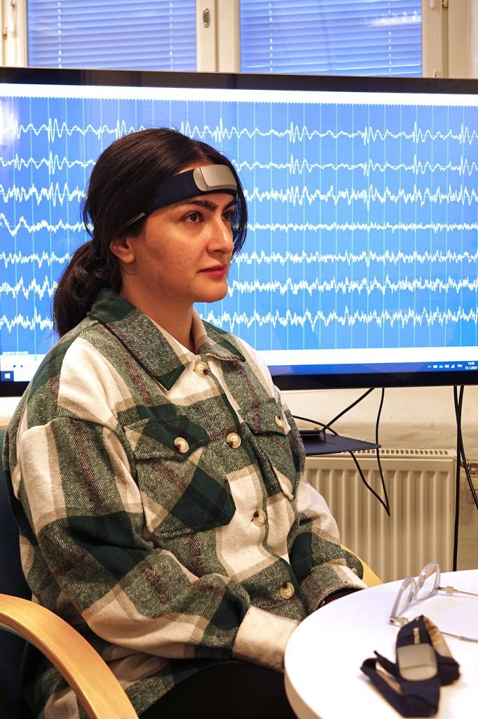 Matin Beiramvand istuu päässään EEG-laite. Taustalla näkyy aivokäyrää ruudulla.
