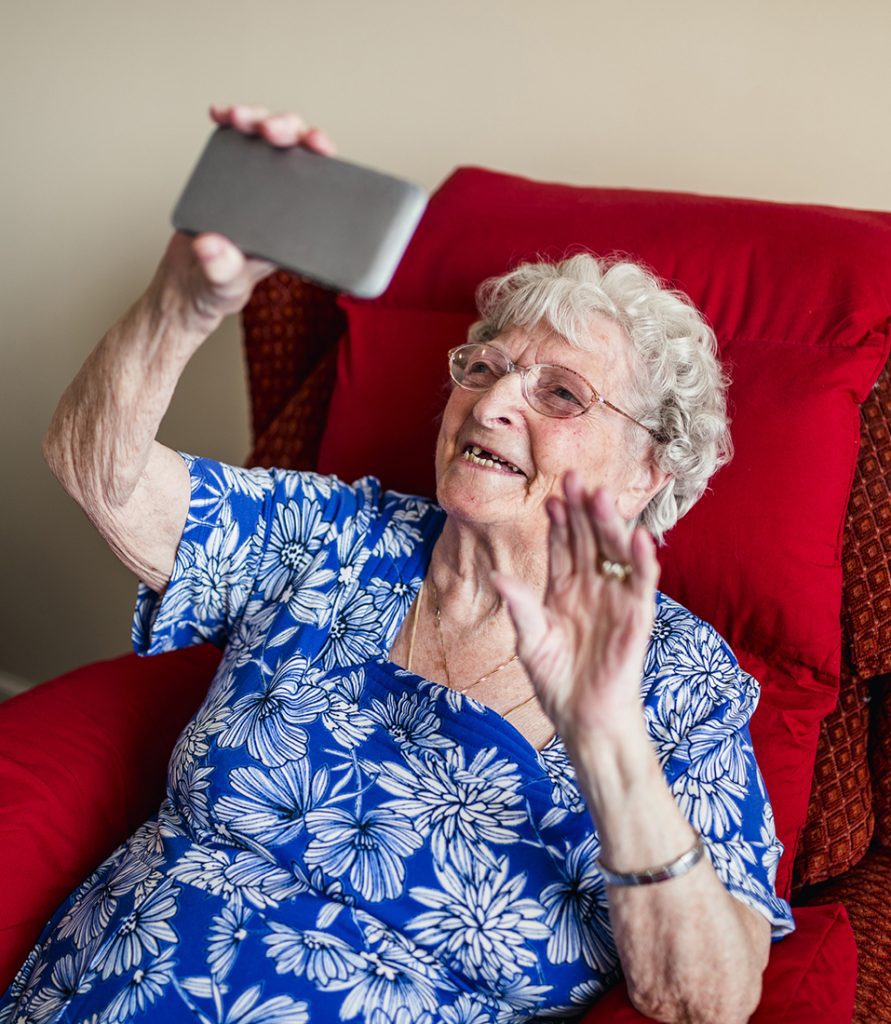 A female senior makes a video call on a mobile device.