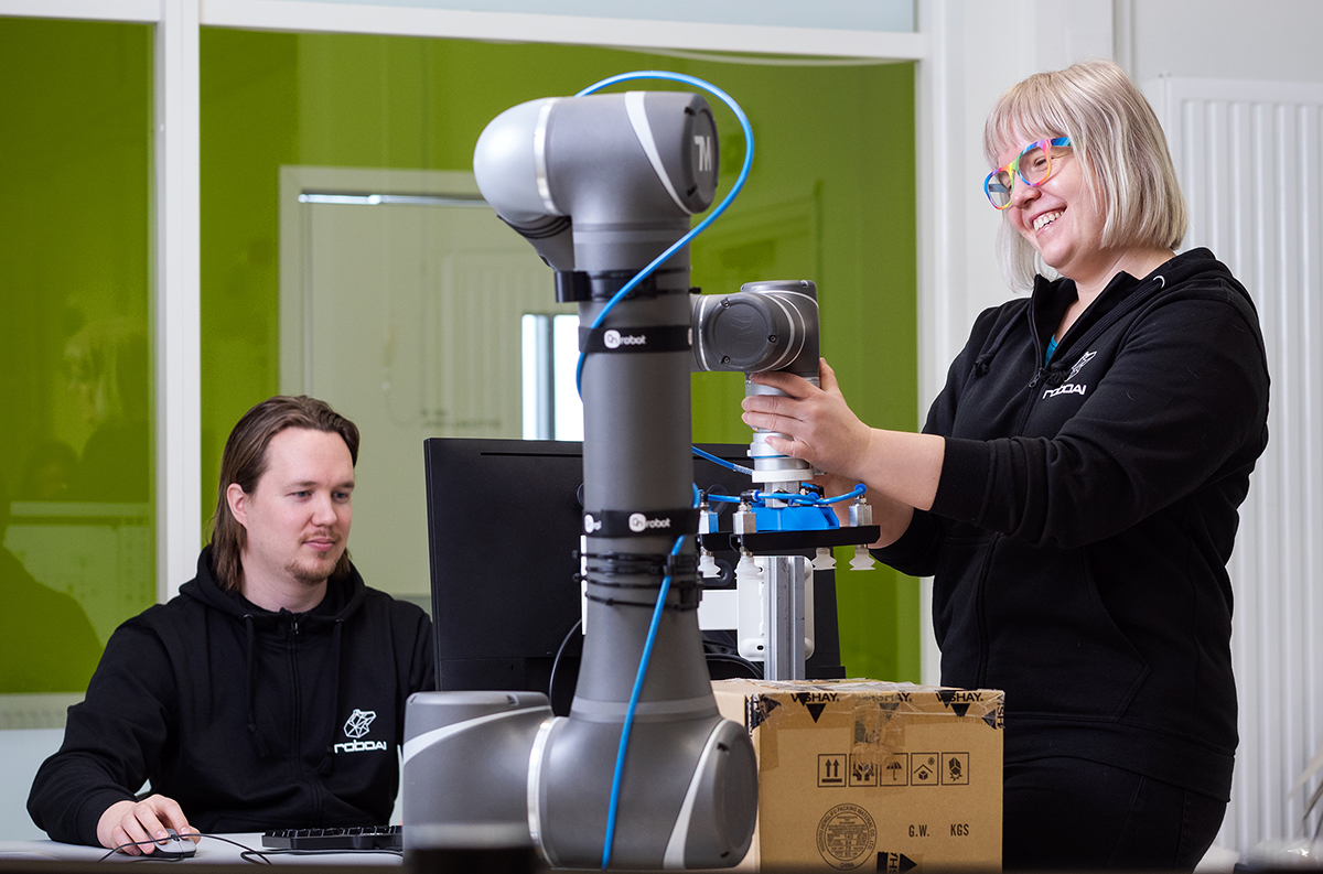 Kaksi opiskelijaa työskentelevät robotin ääressä