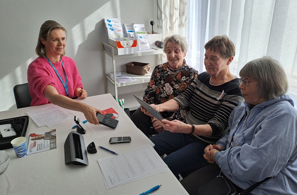 Kolme senioria kokeilee teknologisia laitteita.