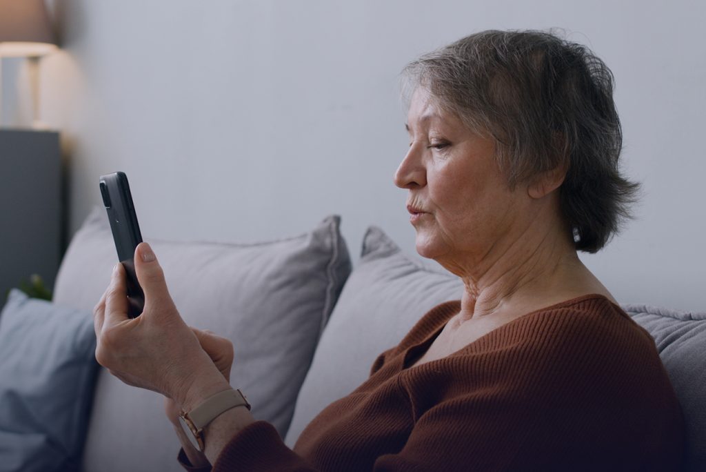An older woman uses a smart phone.