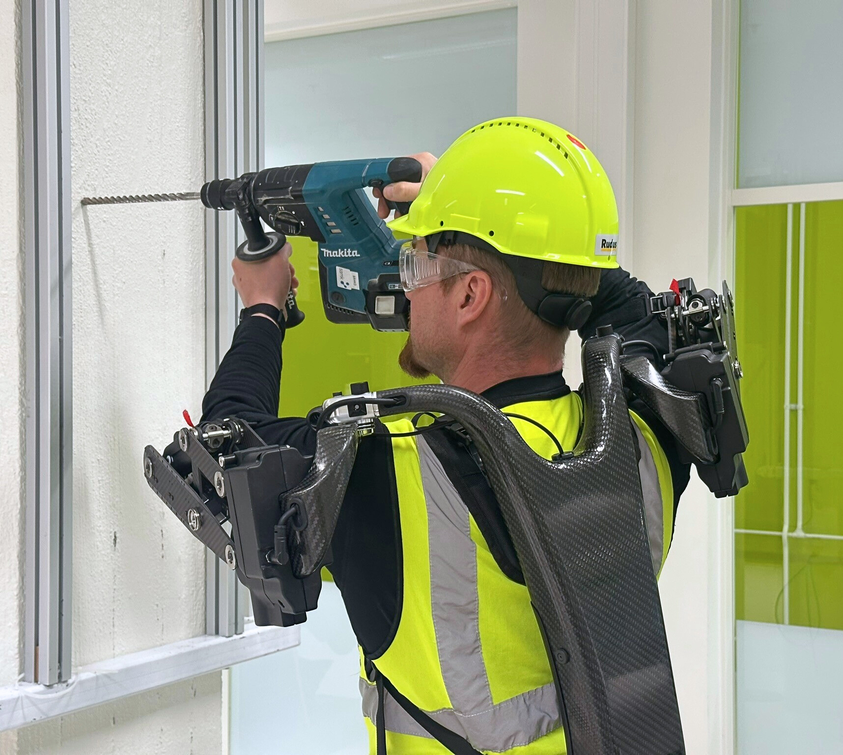 Ekso Artikkelikuva Muokattu Kuvassa mies poraa seinää apunaan exoskeleton.