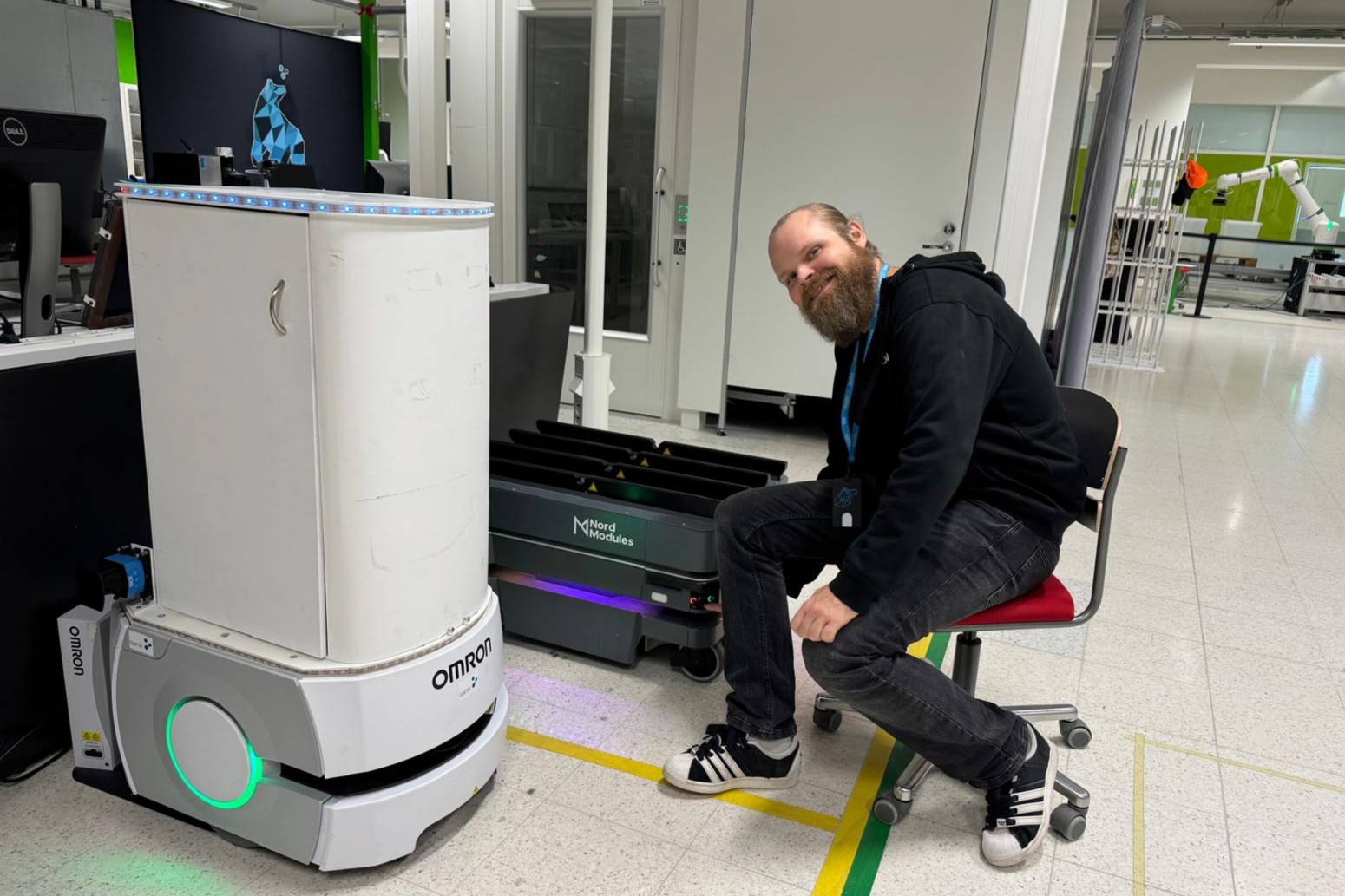 CoRI5.0 Artikkelikuva Mieshenkilö poseeraa kahden mobiilirobotin vieressä