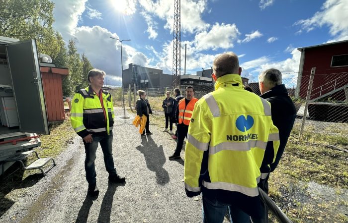Henkilöitä seisomassa ulkona ja keskustelemassa keskenään