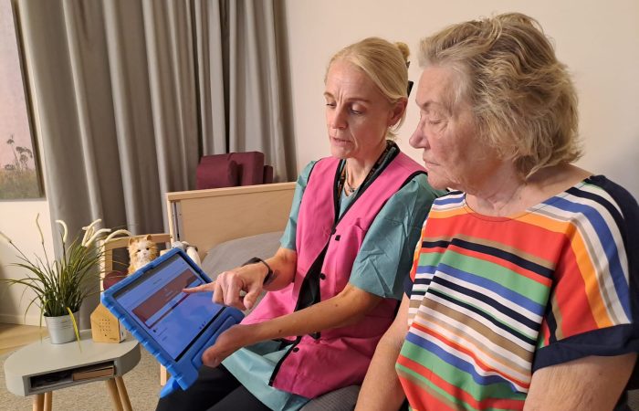 Kaksi naista istuu sohvalla ja katsovat tablettia.