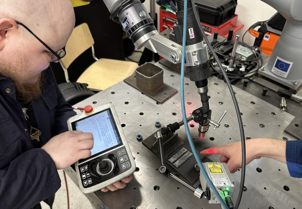 Two men are testing a welding robot.