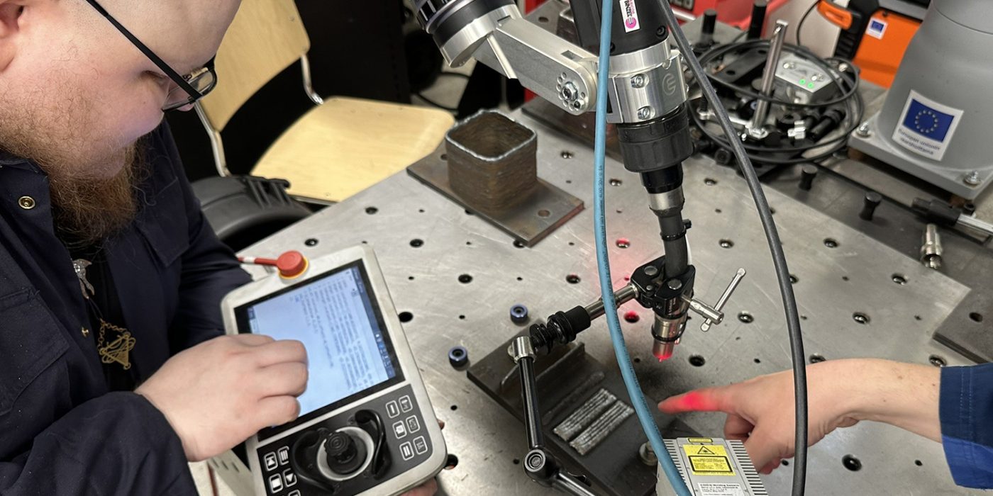 Two men are testing a welding robot.
