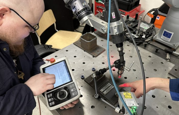 Two men are testing a welding robot.