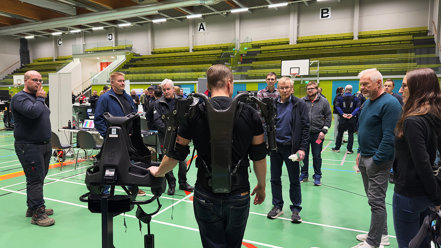 Eksoskeletonit Man dressed in exoskeleton showcasing it to company representatives