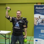 _MG_0475edit Mieshenkilö esittelee eksoskeletonia nostaen kahvakuulaa