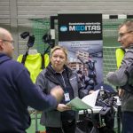 Meditas Naishenkilö esittelee yritysedustajille eksoskeletoneja.