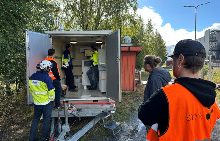 People standing outside and inside of a mobile monitoring trailer