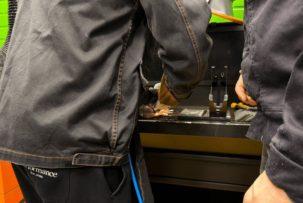 Lähikuva osallistujasta kokeilemassa laserhitsausta.