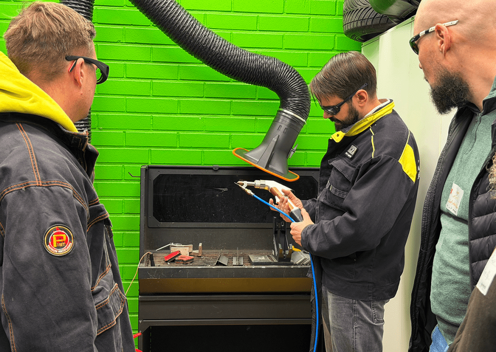 Mies esittellee muille käsilaserhitsauslaitetta