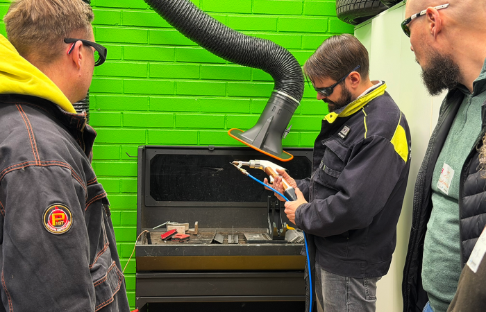 Mies esittellee muille käsilaserhitsauslaitetta