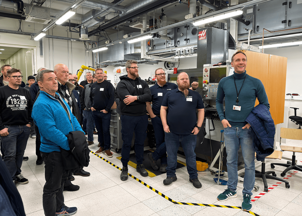 Joukko ihmisiä kokoontuneena konetekniikan laboratorioon.