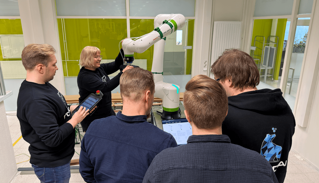 Joukko asiantuntijoita, opiskelujoita sekä yrityksen edustajia kokoontuneena yhteistyörobotin äärelle.