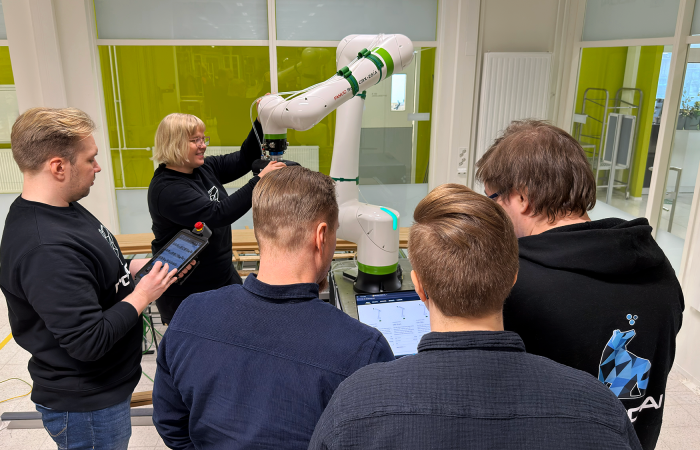 Joukko asiantuntijoita, opiskelujoita sekä yrityksen edustajia kokoontuneena yhteistyörobotin äärelle.
