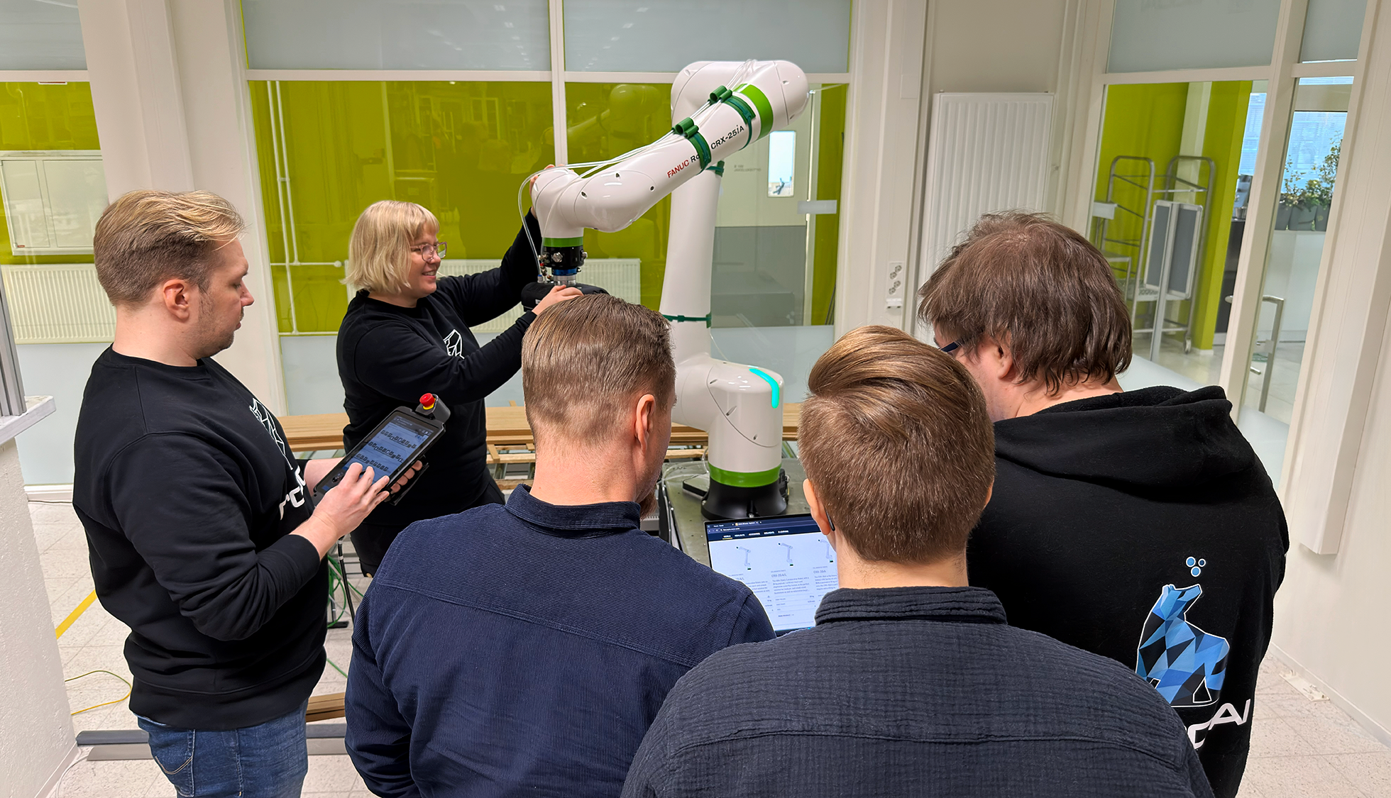 Joukko asiantuntijoita, opiskelujoita sekä yrityksen edustajia kokoontuneena yhteistyörobotin äärelle.