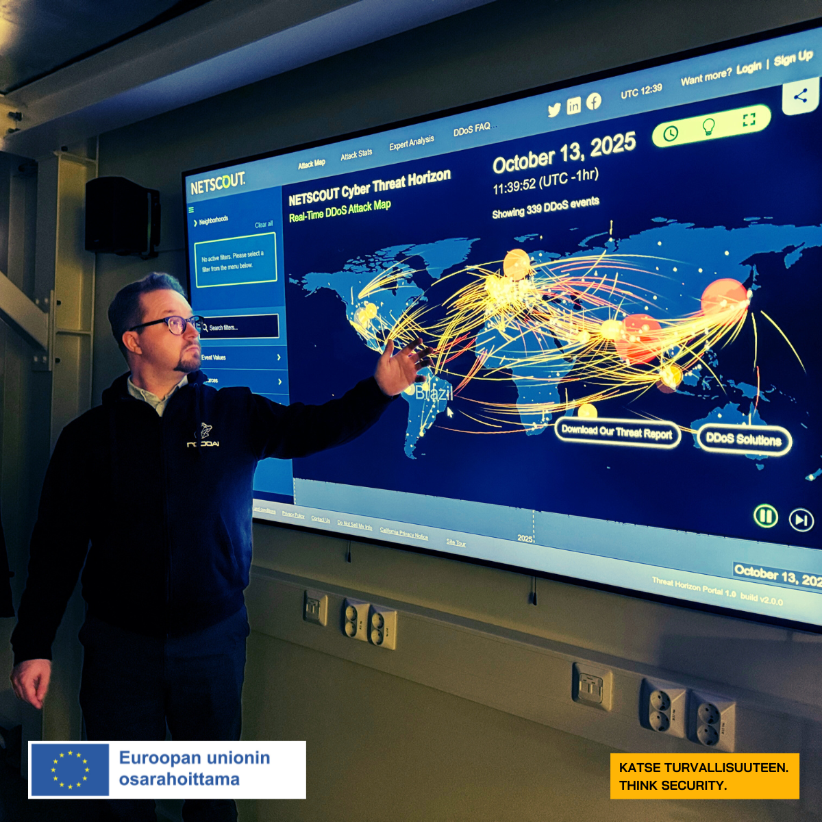 Musta hupparinen mies näyttää näytöltä karttaa, jossa esiintyy kyberhyökkäyksiä