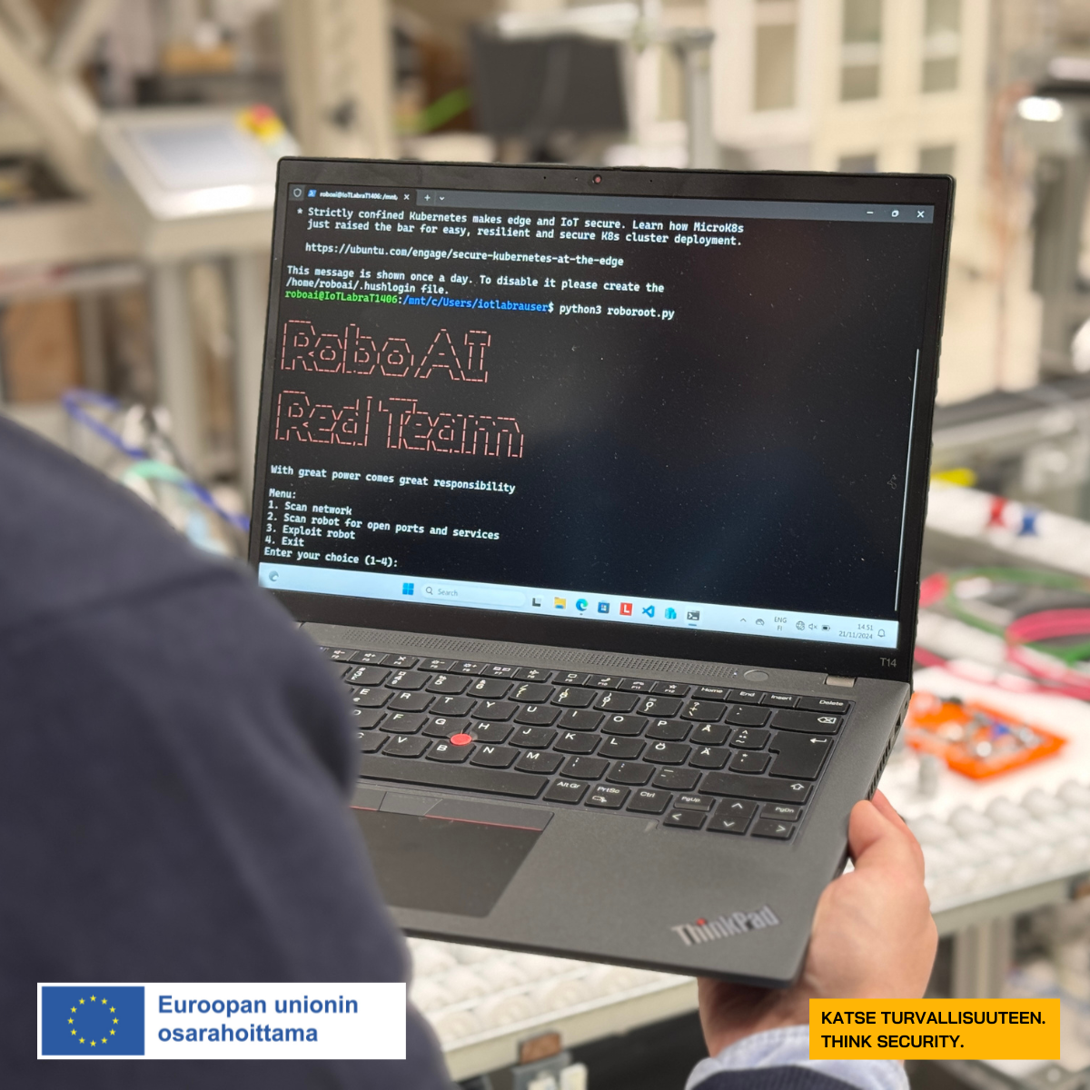 Henkilö pitää läppäriä käsissään ja läppärin näytössä on koodia, jonka keskellä lukee RoboAI Red Team.