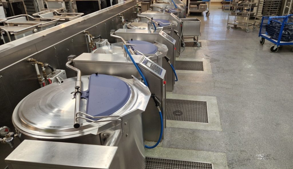 Large ladles in a row in a kitchen environment.