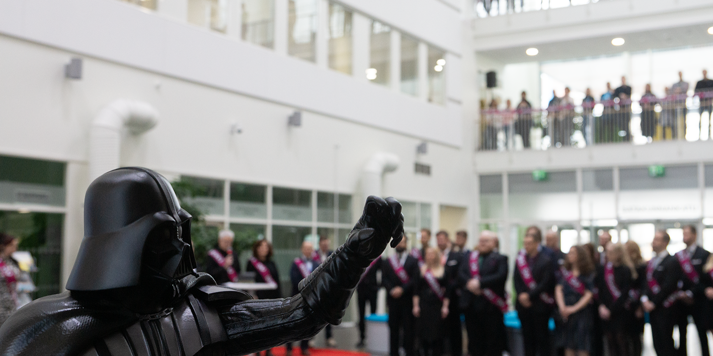 5viides 3D-tulostettu Darth Vader etualalla, takana näkyy juhalyleisöä.