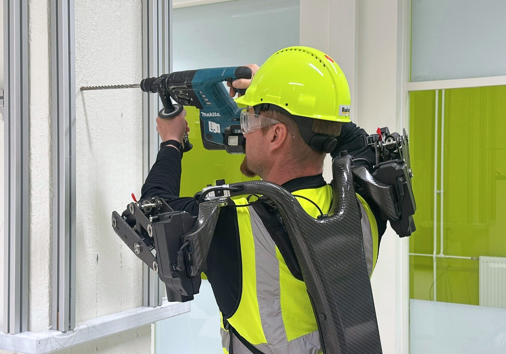 A man holding a heavy drill dressed in exoskeleton